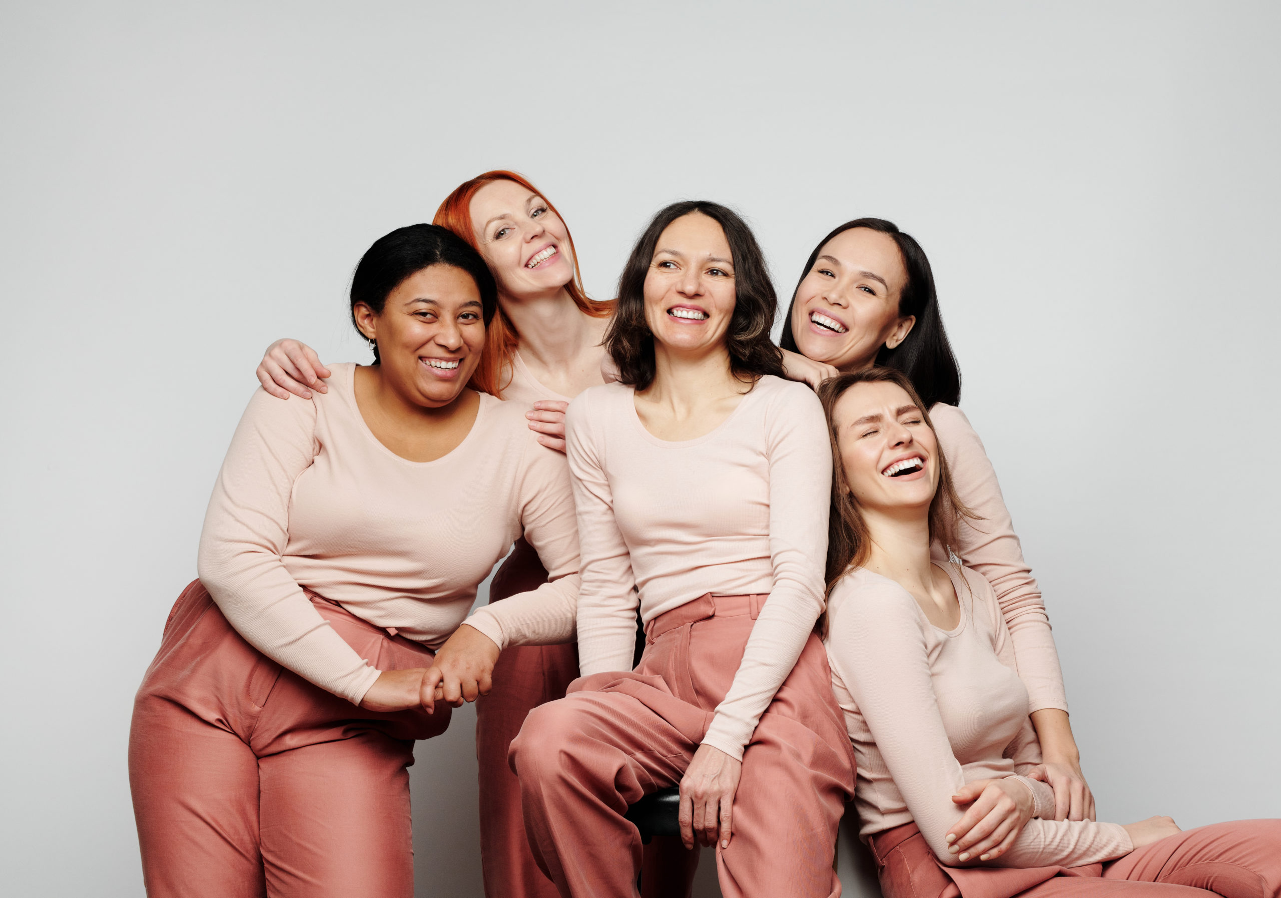Happy excited women of different ethnicities laughing together against white background